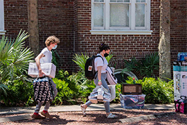 two students carry their belongings into residence halls