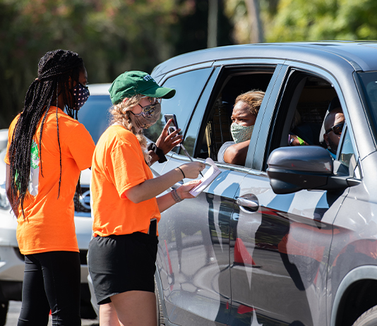 two students talk to a parent inside a vehicle at check-in