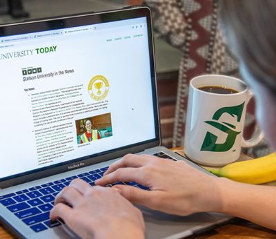 Person in Front of Laptop next to Stetson University Mug.