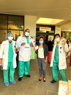 group of doctors hold up ear guards outside the ER