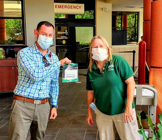 professor and doctor hold a bag of ear guards for face coverings outside a hospital emergency room