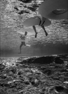 photo of legs in the water under floats