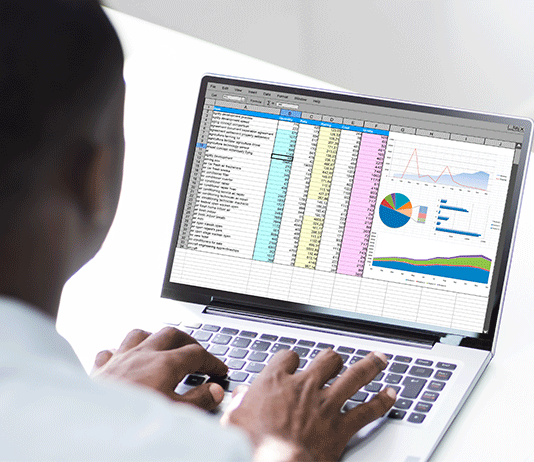 A man sits at his laptop with screen filled with data and graphics.