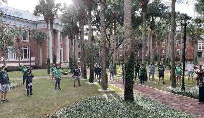 Students stand in Palm Court, physically distanced and wearing masks, to perform.