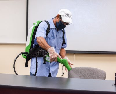 A Facilities crew member uses a fogger to disinfect a classroom.