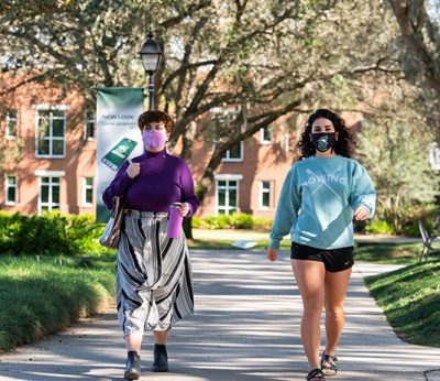 Two students walk on campus in masks during the pandemic