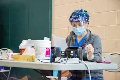 A nurse looks at a COVID testing machine.