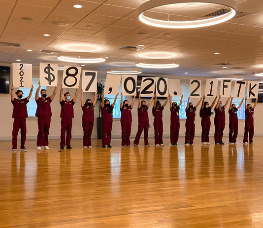 Students hold up a sign with the amount raised: more than $87,000