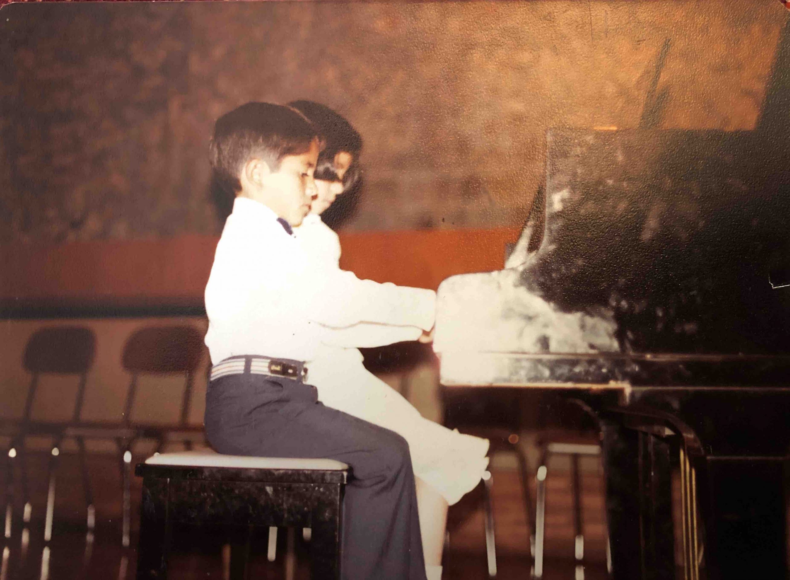 Washington Garcia, as a boy, pratices piano beside his sister.