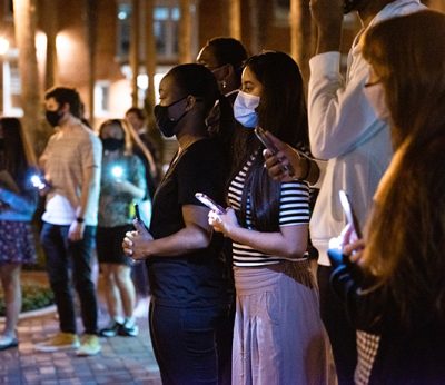 Students stand holding cellphones with the flashlights on, for Year in Review 2021