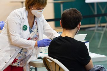 A student gets a vaccine in the Rinker Field House