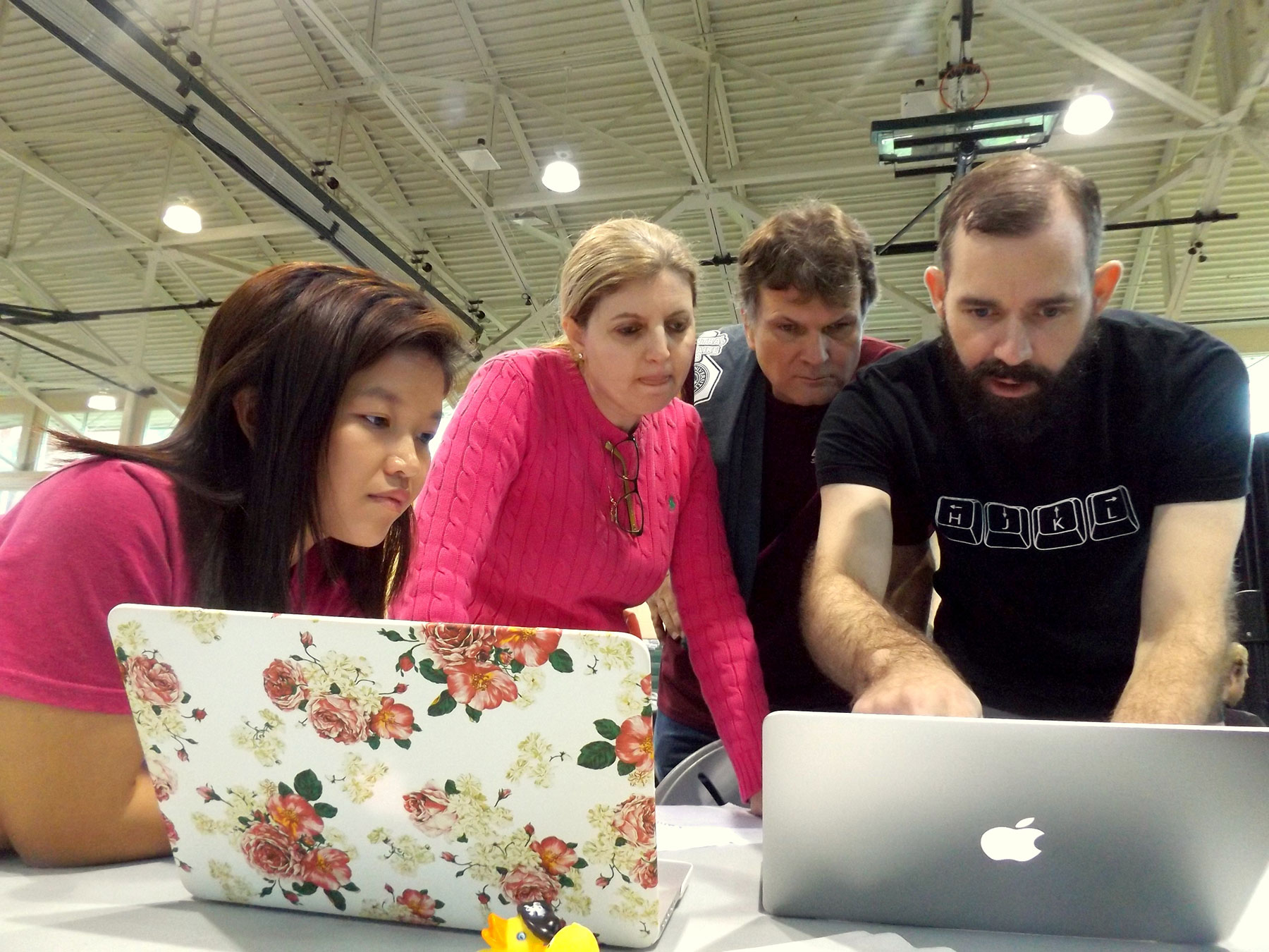 Four people stand looking at laptop computer screens, including Hala ElAarag