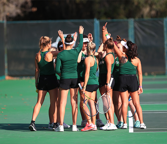 Stetson's women tennis team gives high fives on the tennis court.