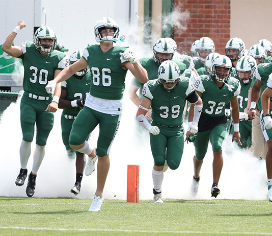 The Hatters football team runs onto the field.