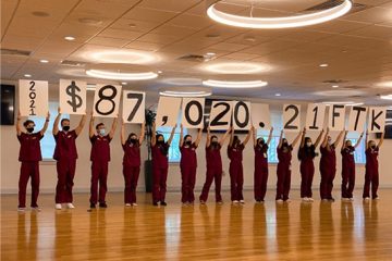 Students hold up signs with the amount raised.