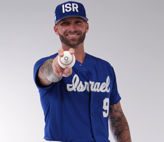 Nick Rickles wears the Israel national team baseball uniform and holds a baseball.