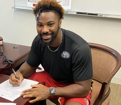 Donald Payne sits at a desk signing papers.