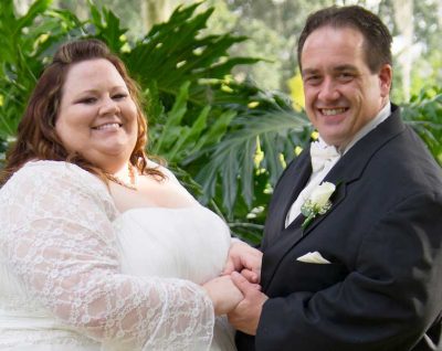 The couple holds hands in a wedding photo