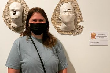 Student stands in front of her winning artwork