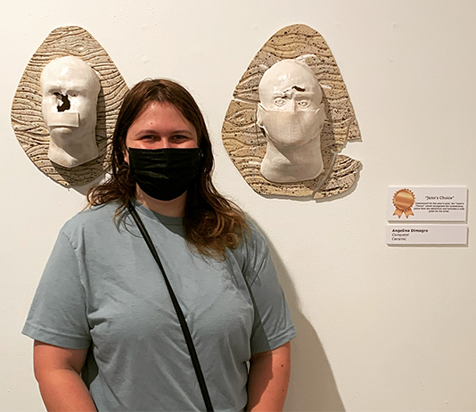 Student stands in front of her winning artwork
