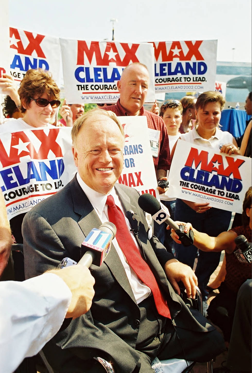 Max Cleland is on a campaign stop with his name on campaign signs all around.