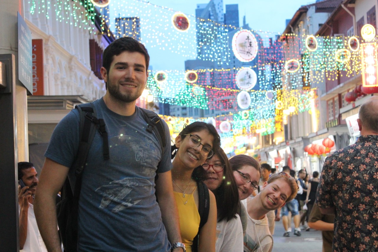 Students visit a pedestrian area in Asia with colorful lights overhead.