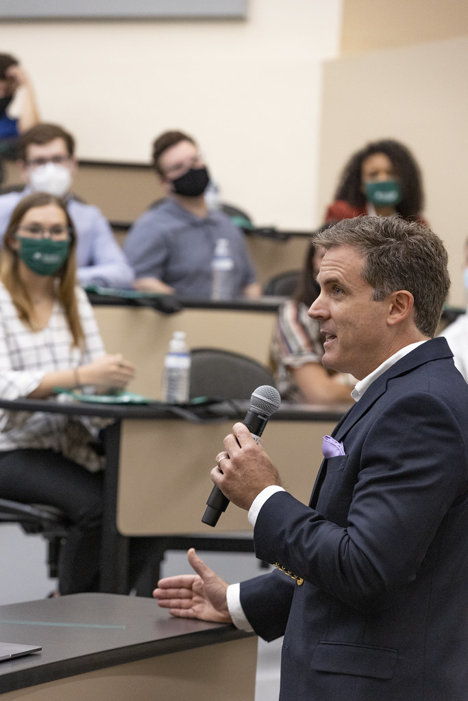 Lou Paris stands in front of an auditorium talking to students about the Hatter Angels Network