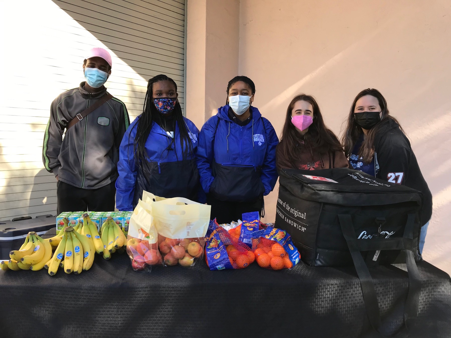 Five Stetson students stand at a table with free breakfast for participants in the MLK Day march.