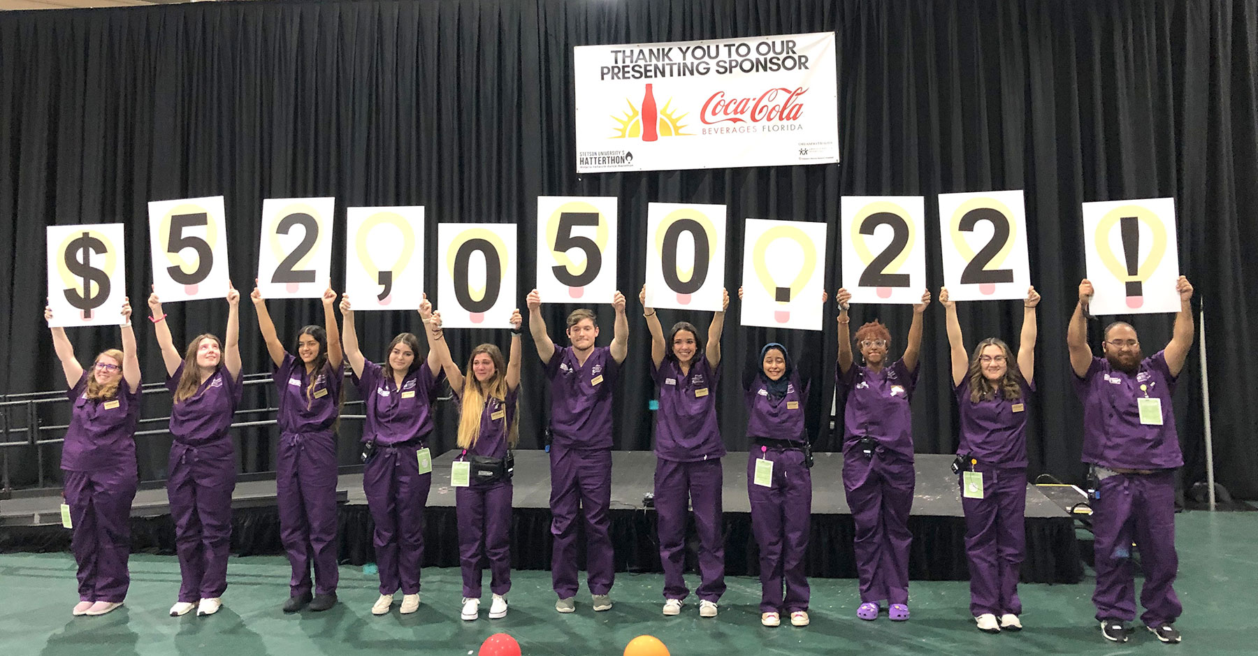 Students hold up sign showing they raised $52K at Hatterthon