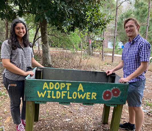 Two students stand in pollination garden