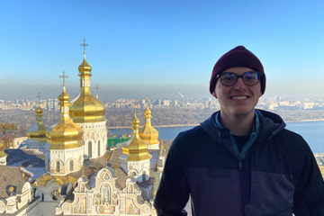 Jonah Helwig in Ukraine with a beautiful church behind him.