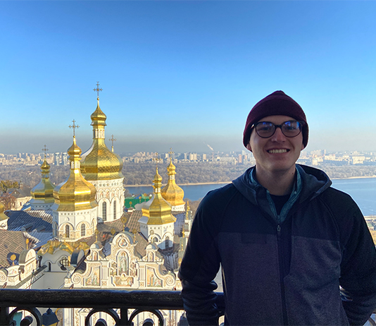 Jonah Helwig in Ukraine with a beautiful church behind him.