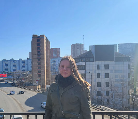 Student stands on a balcony in Russian city.