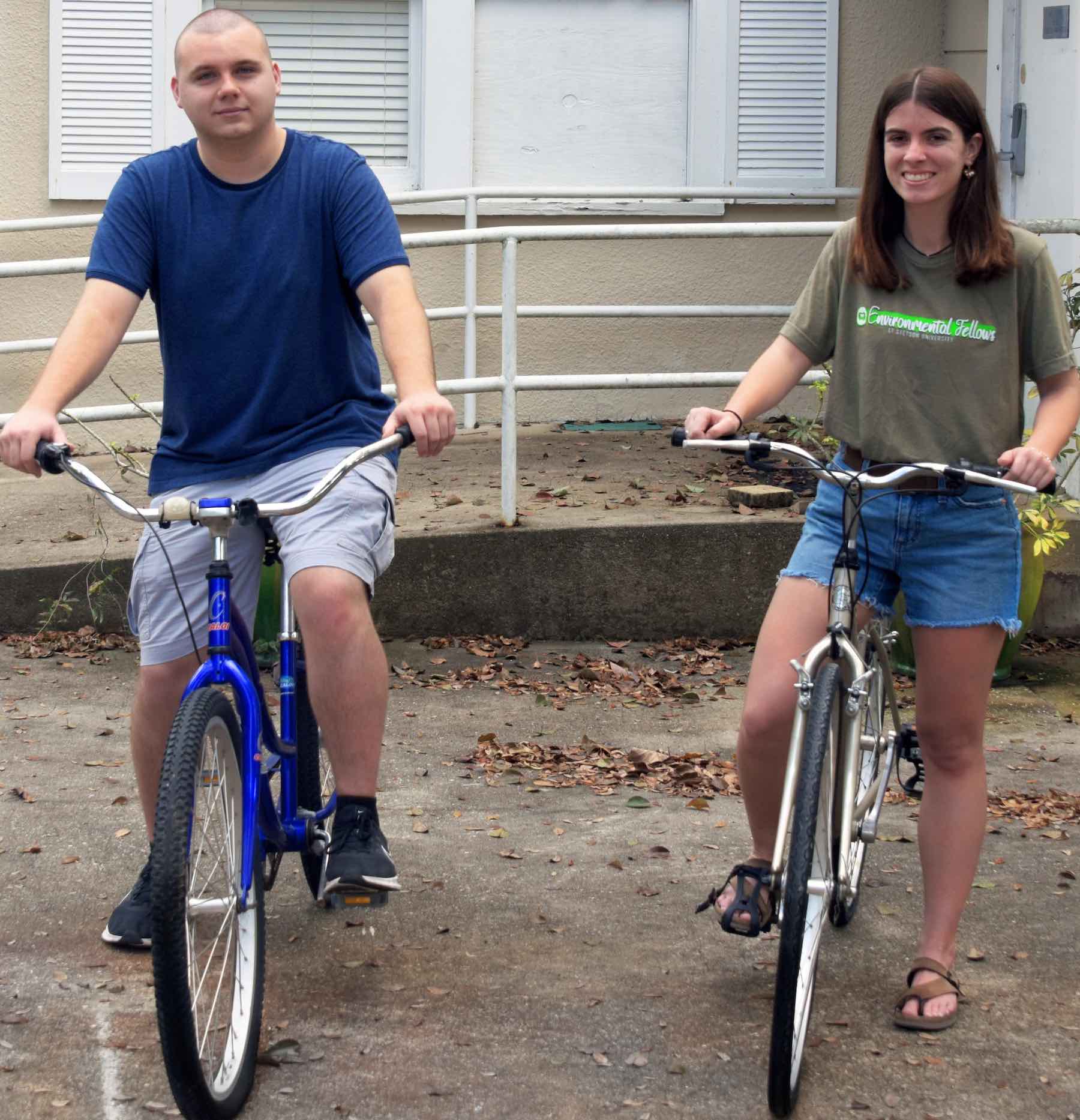 Two students pose on bicycles