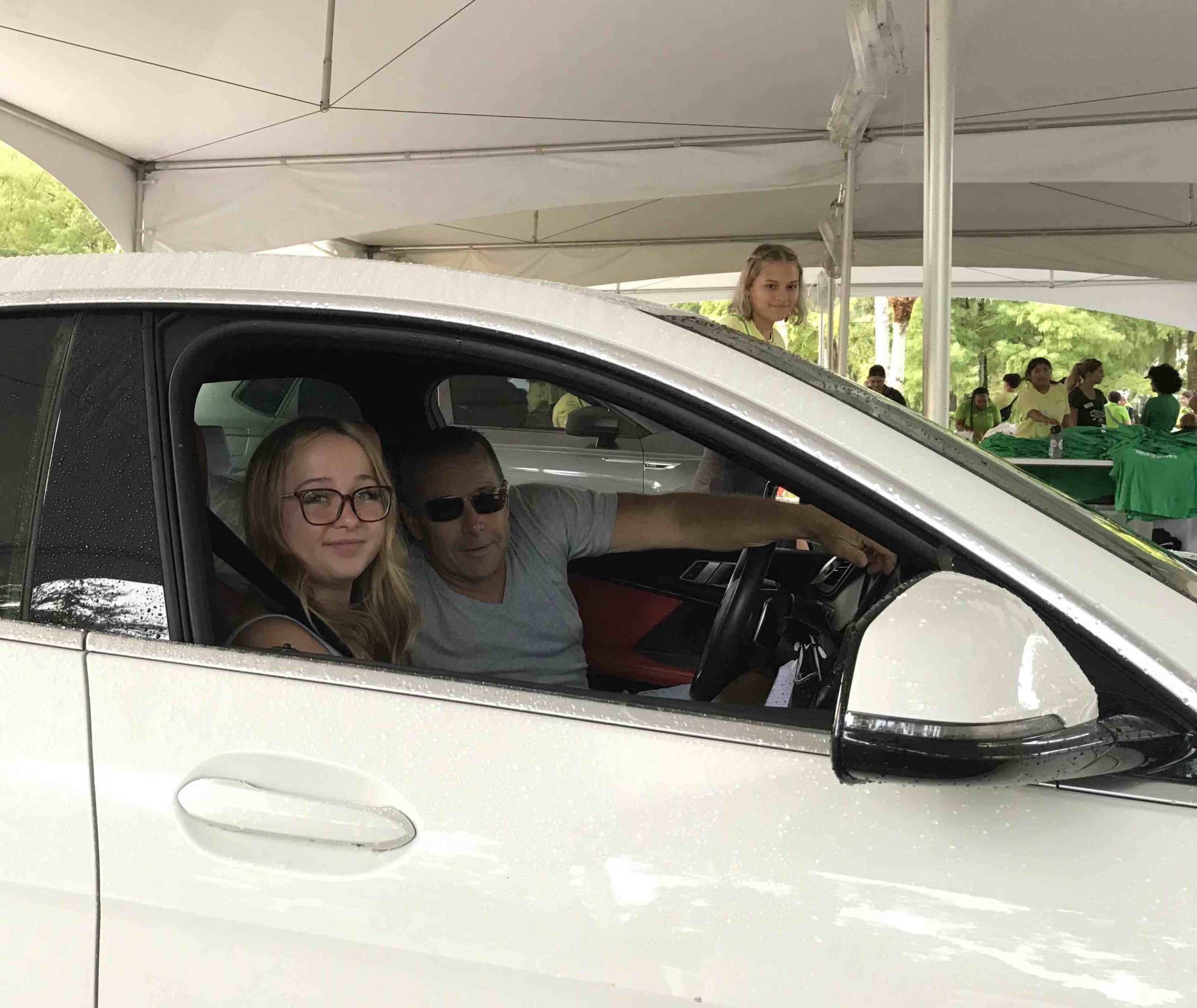 A student and her father pose in their car during drive-thru check-in on Move-In Day 2022.