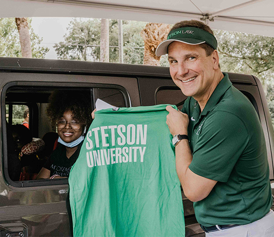 President Roellke holds up a Stetson t-shirt to give to an arriving student.