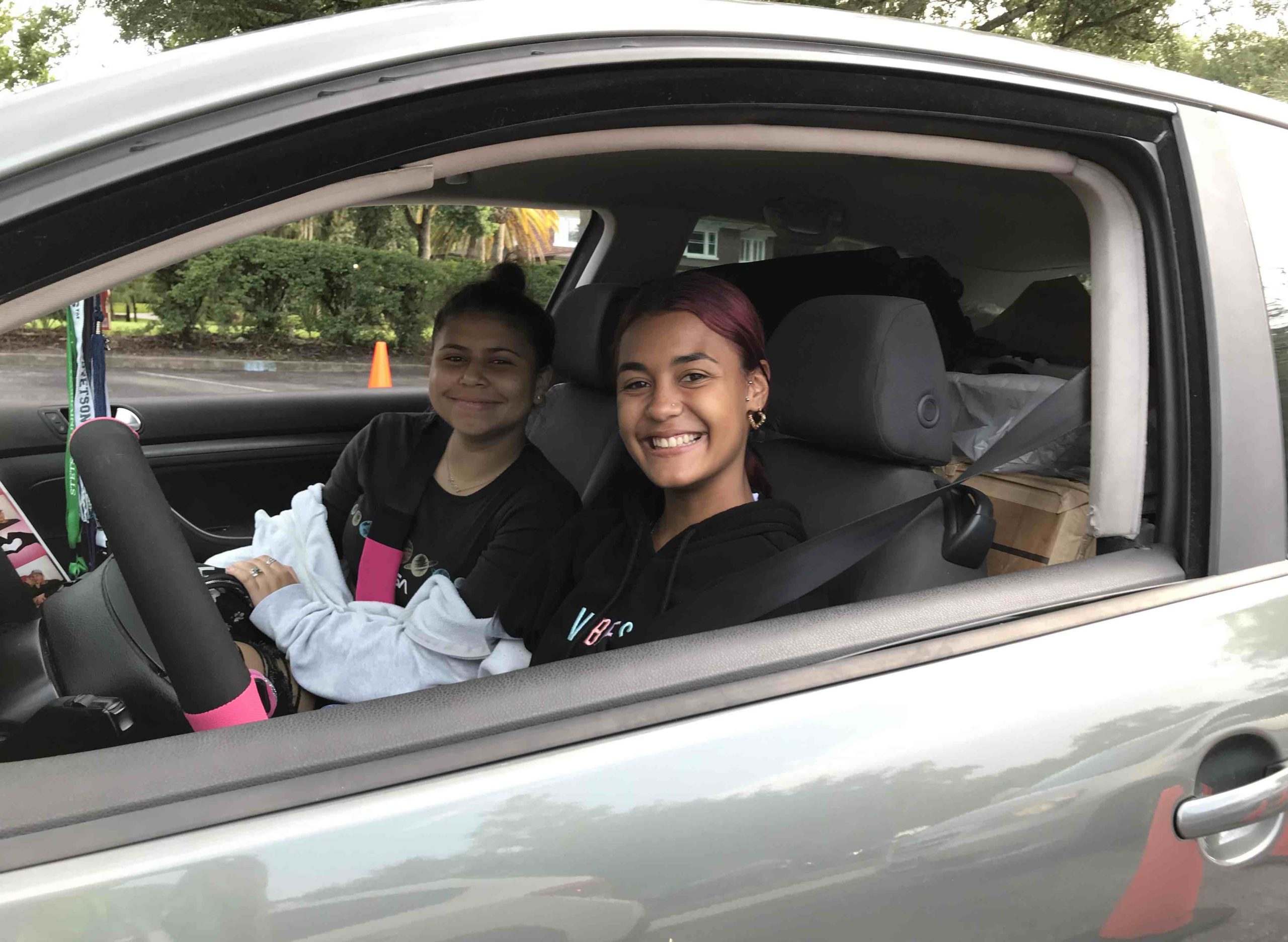 A student and a friend pose in their car during drive-thru check-in at Move-In Day 2022.