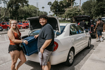 Two people stand at the trunk of car unloading on Move-In Day 2022
