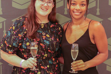 Two students pose with champagne glasses.