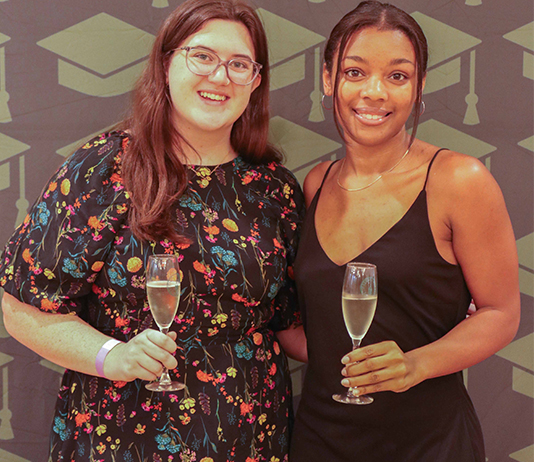 Two students pose with champagne glasses.