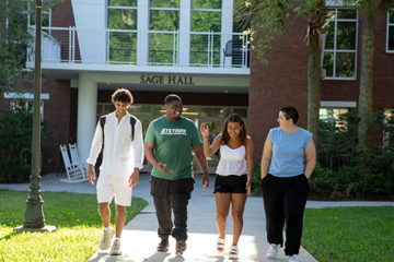 A group of students walk outside Sage Hall
