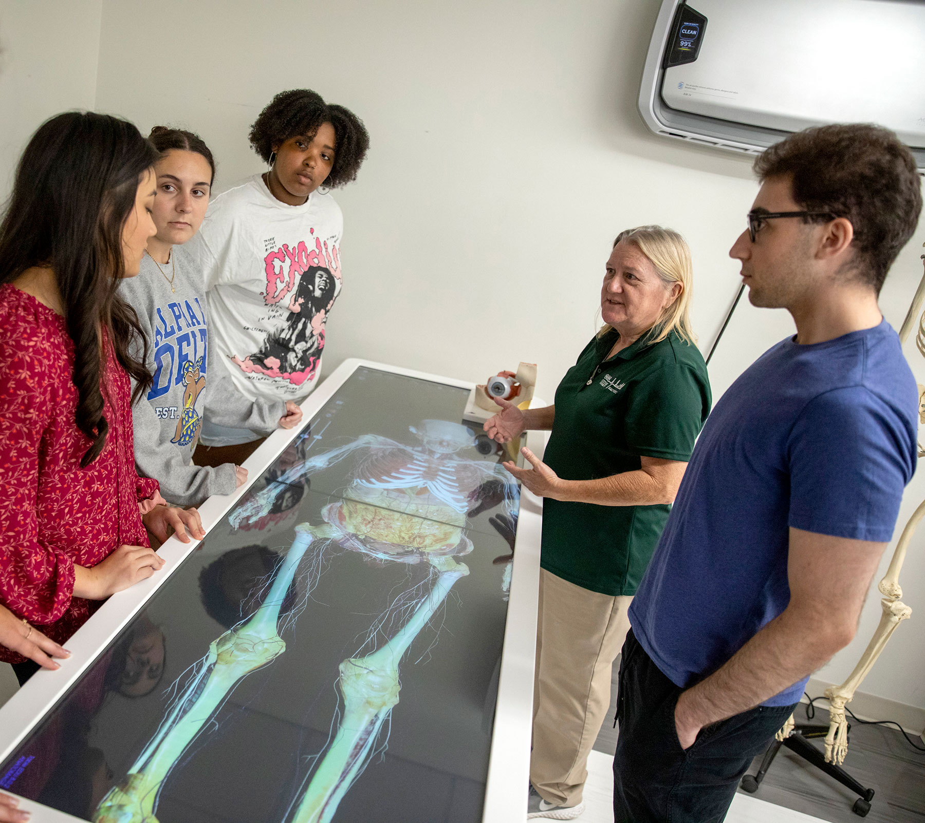 Professor and students stand around a 3D anatomy / virtual dissection table.