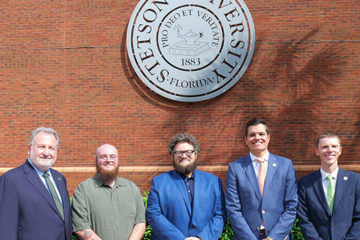 Group photo of Stetson and OEP officials standing in front of the Stetson seal.