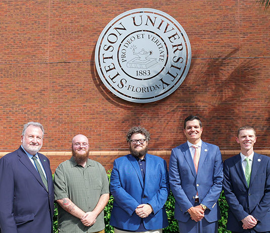 Group photo of Stetson and OEP officials standing in front of the Stetson seal.