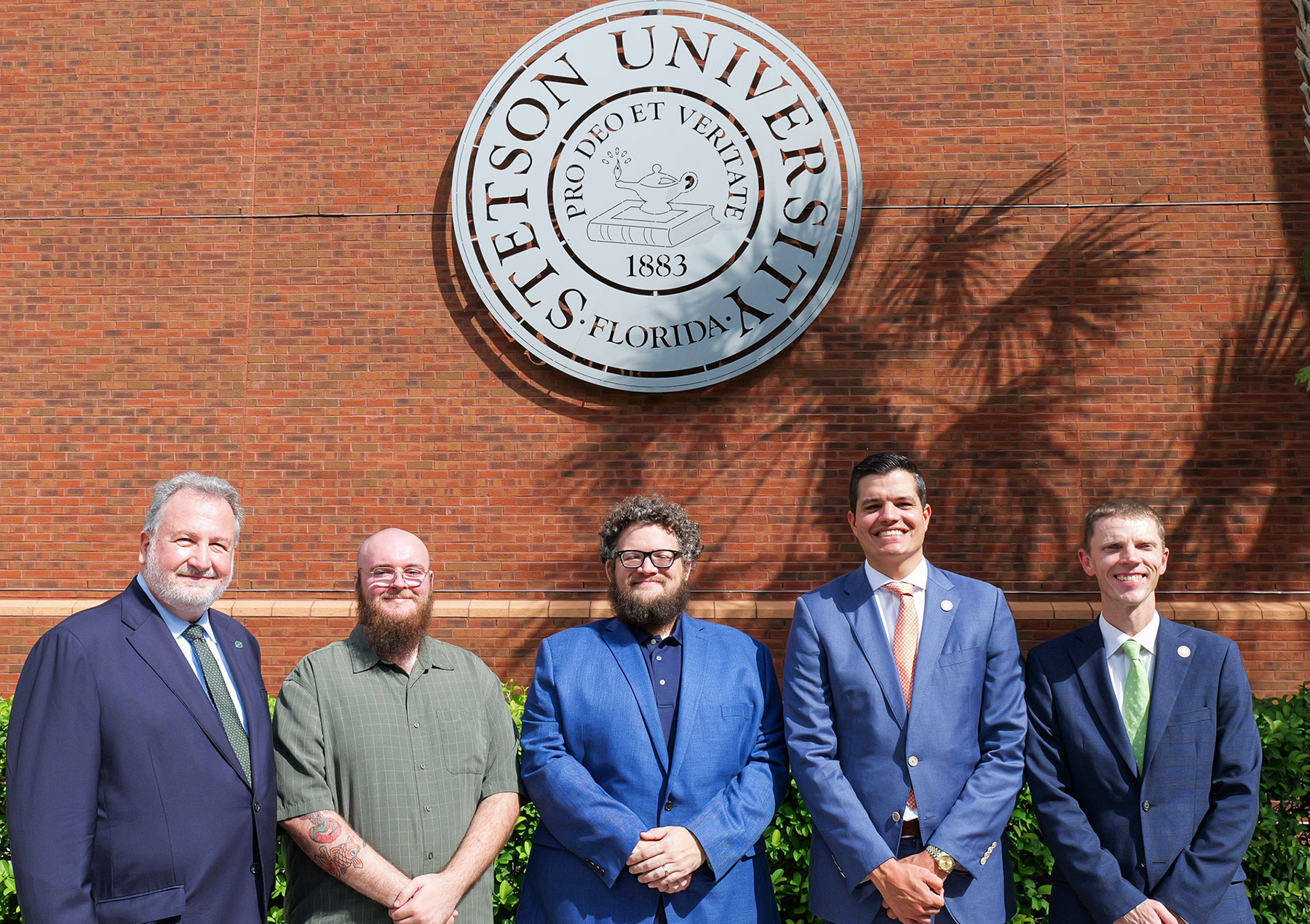 Group photo of officials from Stetson and Orlando Economic Partnership in front of Stetson seal