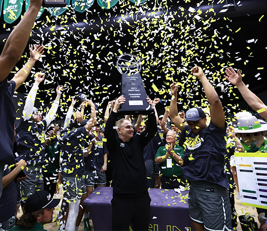 Coach holds ASUN trophy during celebration