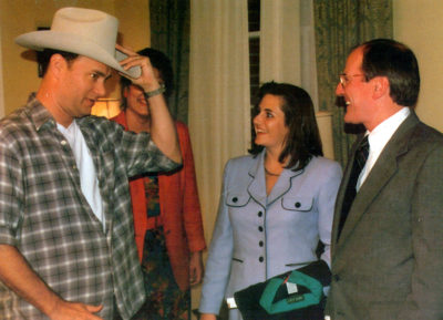 Actor Tom Hanks tries on a Stetson Hat while other watch.
