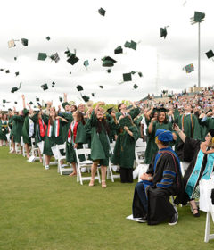 Graduates throw their graduation caps in the air at Commencement