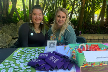 Two students sit at a table with buttons and other giveaways.
