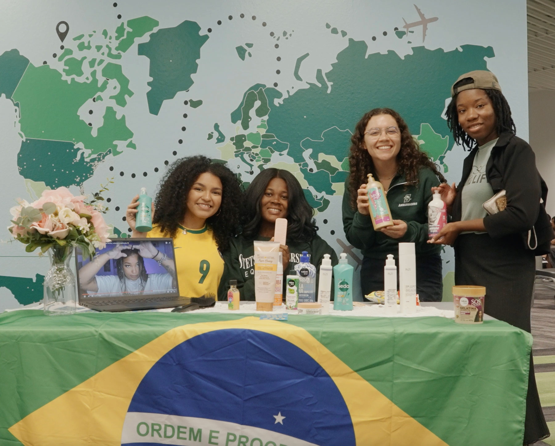 Four students hold hair care products at Stetson's Hairitage event